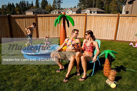 Family in yard with children's pool and cocktails