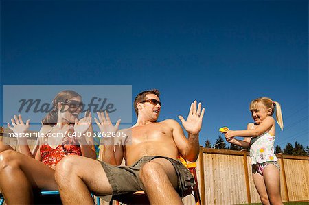 Boy spraying man and woman with hose