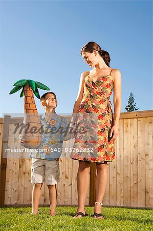 Woman holding hands with boy holding inflatable palm tree