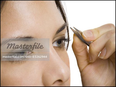 Closeup of woman tweezing eyebrows