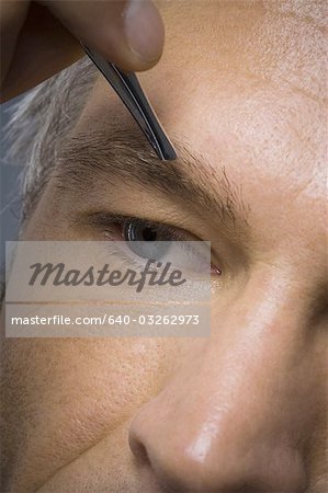 Closeup des Mannes mit der Pinzette Zupfen der Augenbrauen