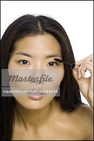 Closeup of woman applying mascara smiling