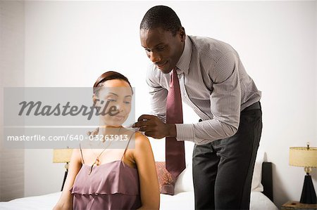 Man doing up a woman's necklace clasp