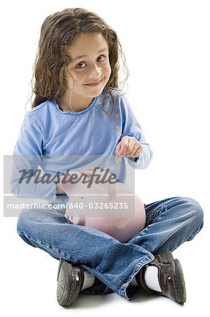 Young girl depositing money in piggy bank