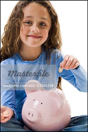 Young girl depositing money in piggy bank