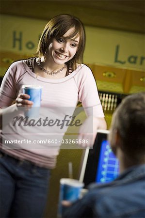 Teenager-Mädchen hält ein Einweg Glas Cola und Blick auf einen jungen Mann