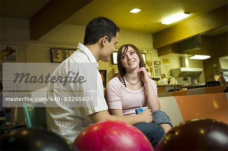 Vue d'angle faible d'un jeune homme assis avec une adolescente dans un bowling