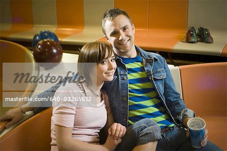 Porträt von einem jungen Mann und ein junges Mädchen sitzt in einer Bowlingbahn