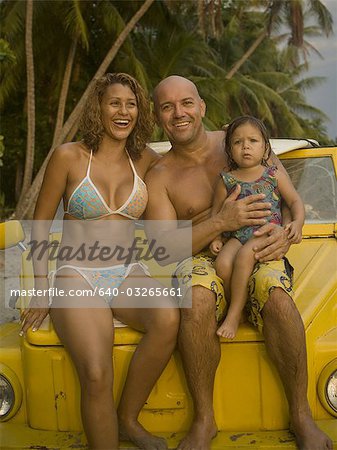Portrait of a family sitting on their car
