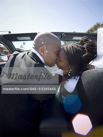 Vue arrière d'un couple de jeunes mariés s'embrasser dans une voiture