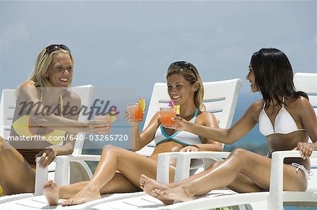 Three young woman celebrating by the pool