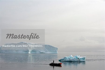 L'Antarctique, la péninsule Antarctique, Paradise Harbour. Un pilote du zodiaque le navire d'expédition la découverte MV explore Paradise Harbour avec un énorme iceberg tabulaire mise à la terre comme toile de fond.