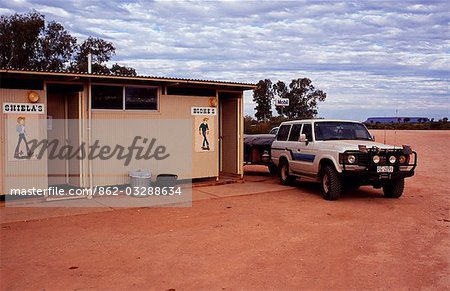 Roadside Public toilet,with classic Australian signs - Sheilas and Blokes - beside a road through the Outback