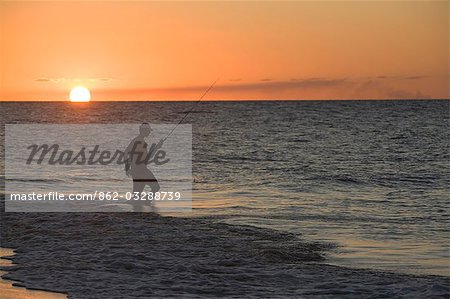 A fishermen wades into the surf as the sun sets on Fraser Island.