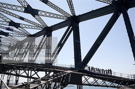 Un groupe d'alpinistes mise à l'échelle de l'arc de la suspension du Sydney Harbour Bridge est éclipsée par des poutres d'acier de la structure au-dessus du port