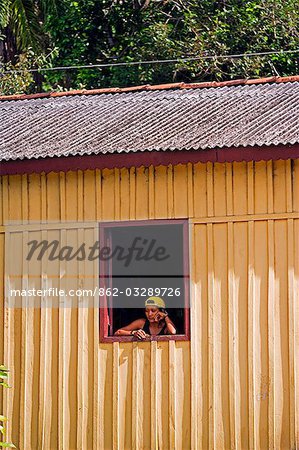 Brésil, Amazonie, Rio Tapajos. Un affluent de la Tapajos Rio qui est elle-même un affluent de l'Amazone. Une femme dans le village de Maguari regarde la vie passer devant sa fenêtre.