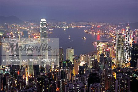 View over Hong Kong from Victoria Peak. The illuminated skyline of Central sits below The Peak with the lights of Tsim Sha Tsui in Kowloon across the harbour.