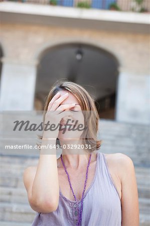 woman covering her eyes smiling