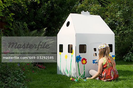 A girl painting a cardboard wendy house