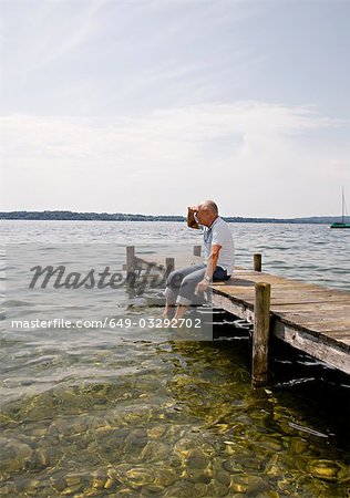 senior man sitting on pier at lake