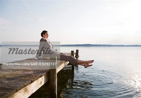 femme assise sur la jetée au lac