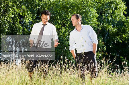 two businessmen talking in field