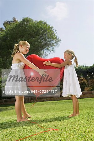 Jeunes filles s'enlaçant ballon coeur rouge