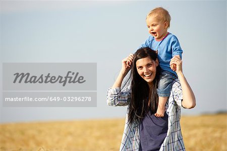 Woman with baby on shoulders, outdoors