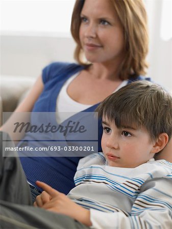 Mother and son (5-6) watching television on couch