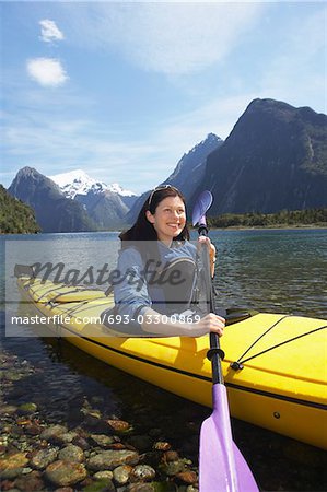Femme pagaie de kayak en lac de montagne