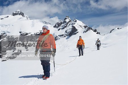 Three hikers joined by safety line in snowy mountains