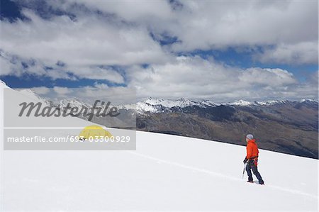 Wanderer zu Fuß in Richtung Zelt in verschneiten Bergen