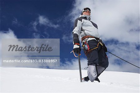 Mountain climber standing on snowy slope with safety line attached