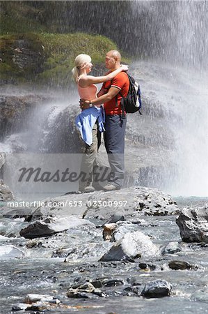 Couple embracing under spray of waterfall