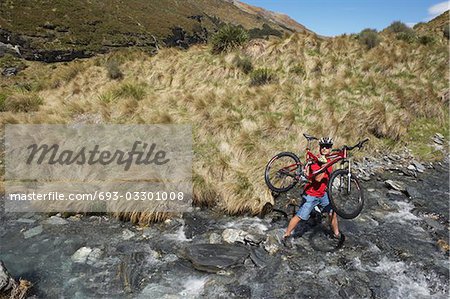 Cyclist carrying bike in river