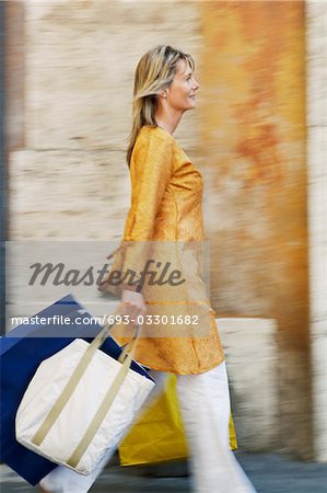 Woman Walking with Shopping Bags on street in Rome, side view