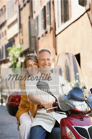 Couple d'âge mûr sur la trottinette dans la rue en portrait de Rome (Italie),