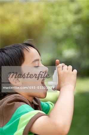 Little boy in park using inhaler