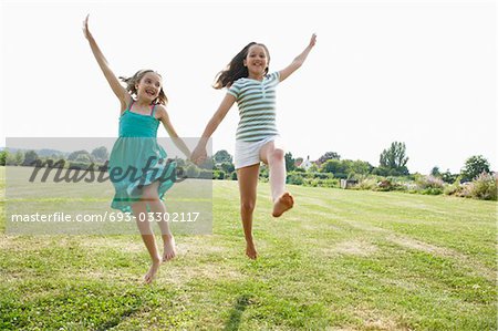 Girls Running and jumping Hand in Hand through field