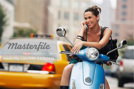 Frau mit Handy auf moped