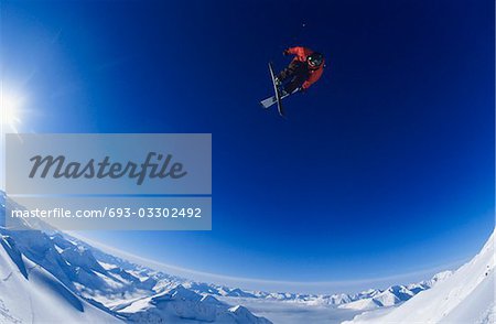 Skieur sautant, sur fond de ciel bleu