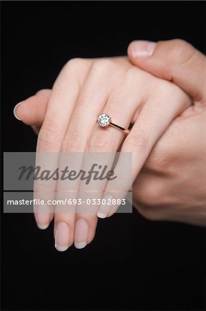 Man holding woman's hand displaying engagement ring, close up of hand