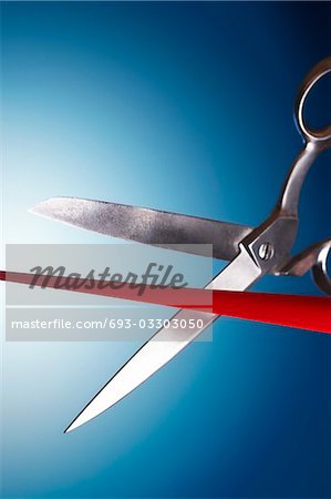 Scissors cutting red ribbon in studio