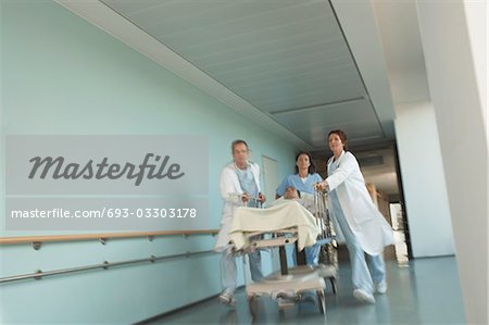 Ärzte Rauschen Patient auf Gurney Down Krankenhaus Korridor