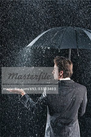Geschäftsmann Hand ragte unter Dach zu fühlen, Regen, Rückansicht