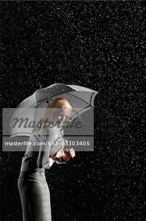 Femme d'affaires arrondir vers le bas sous le parapluie de protection contre la pluie