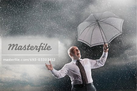 Homme d'affaires, tenir le parapluie, riant dans la tempête, à faible angle vue