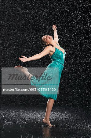 Woman standing on one leg, leaning into falling rain