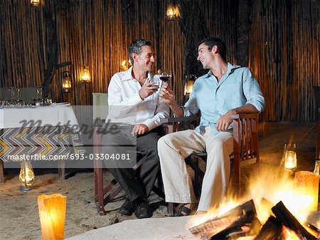 Deux hommes assis autour d'un feu dans la discothèque en plein air, grillage