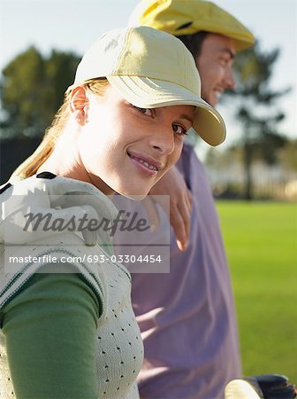 Two young golfers on court, focus on woman